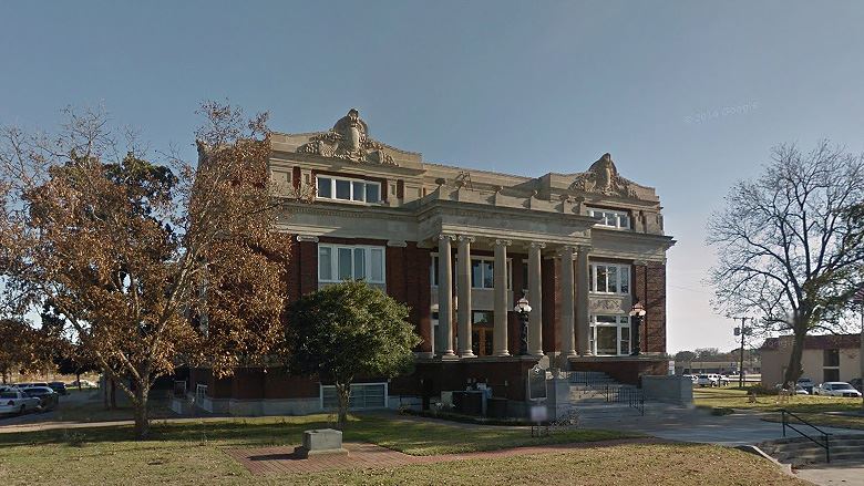 A large brick building with columns
Description automatically generated